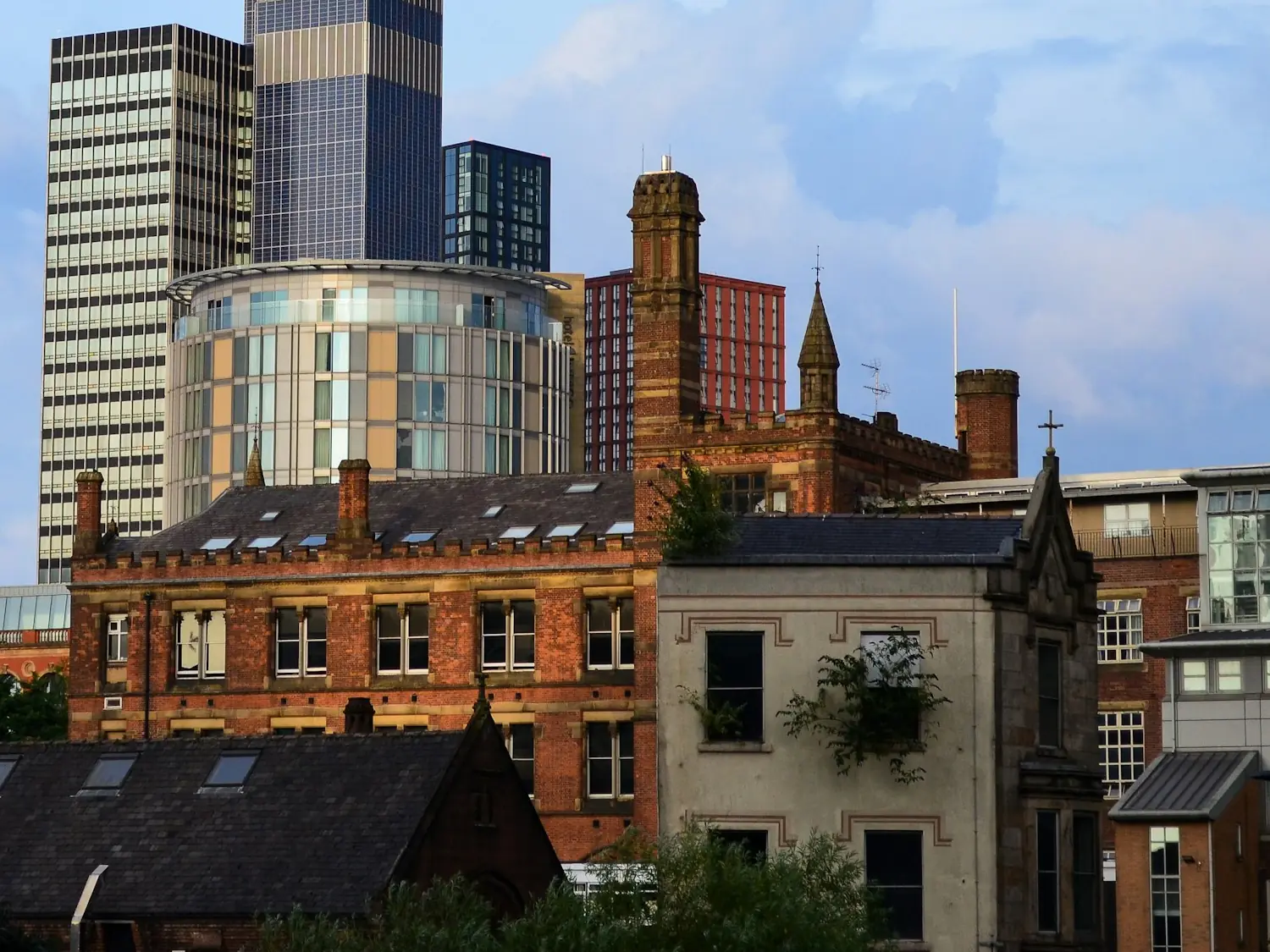 Manchester’s skyline: glass towers rising behind Victorian red-brick warehouses and slate roofs.