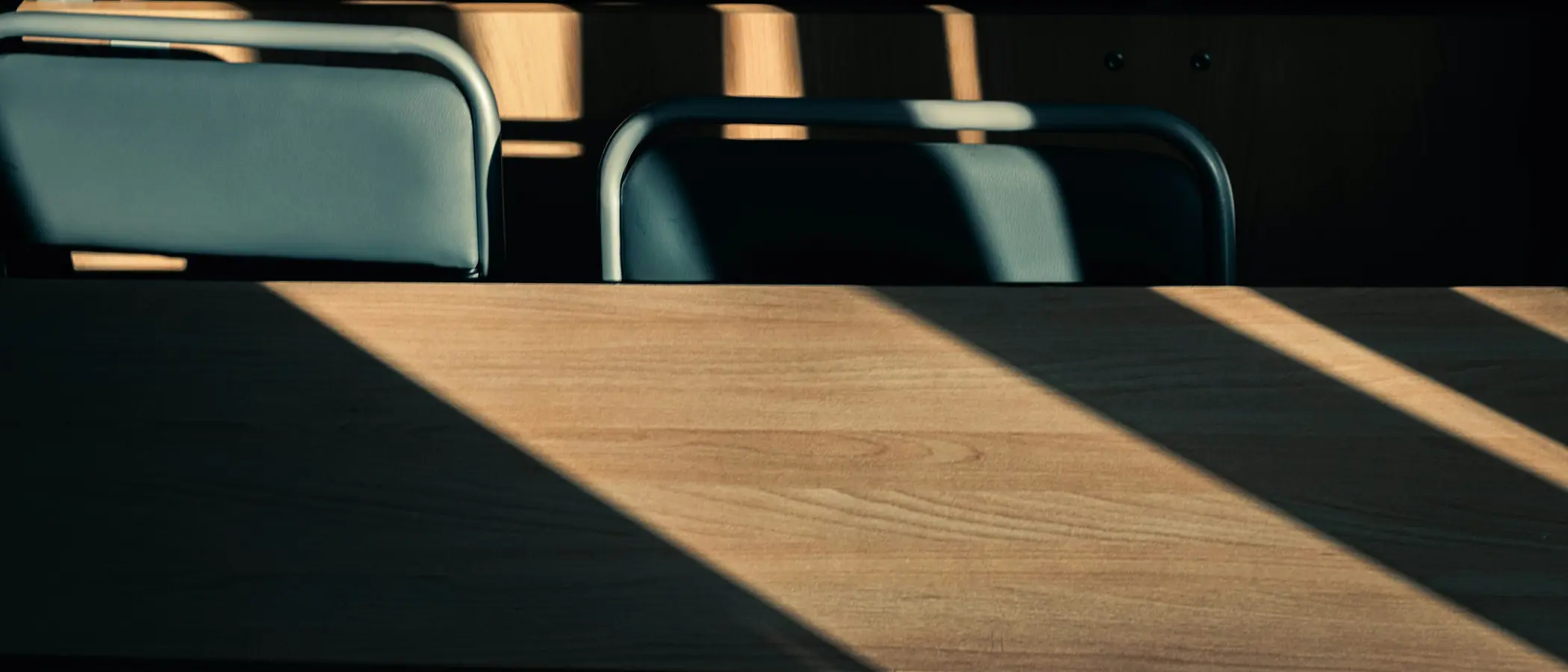 Morning sun across rows of empty desks, the chairs still pushed in.